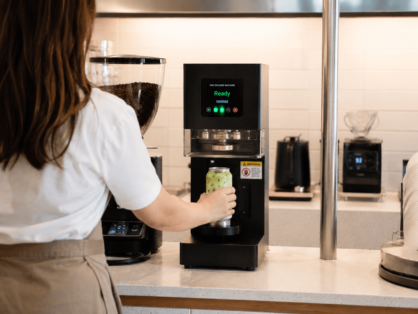 A barista sealing a fresh can on the Canned seamer